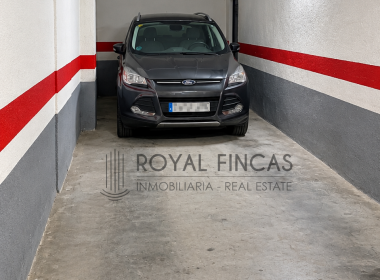 Garaje subterráneo con SUV y marca inmobiliaria